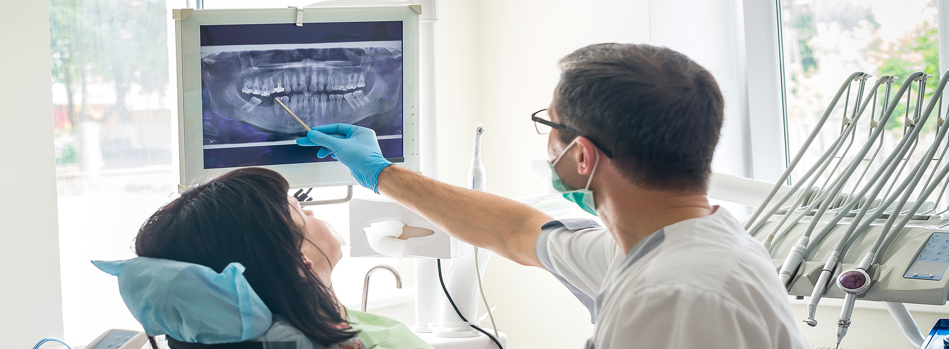 This image shows a medical professional, likely a nurse or doctor, interacting with an elderly patient who is lying in a hospital bed. They are focused on the patient s face. The setting appears to be a hospital room with medical equipment and monitors visible.