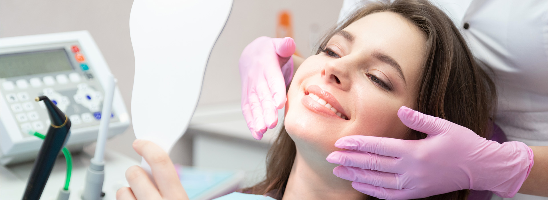 A woman is seated in a dental chair, receiving oral care from a dentist.