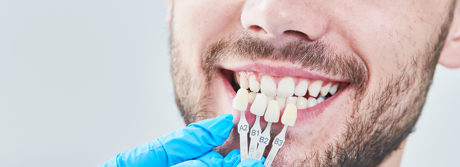 A man in a blue surgical gown undergoing dental treatment, with a tooth being prepared for a dental implant.